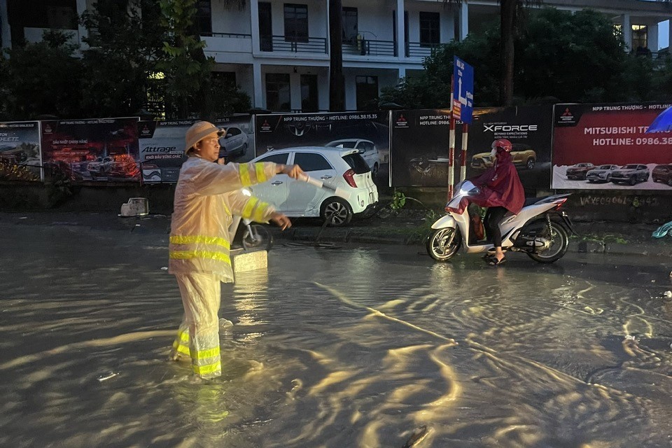 Cảnh sát giao thông dầm mưa giúp đỡ người dân di chuyển qua các điểm úng ngập